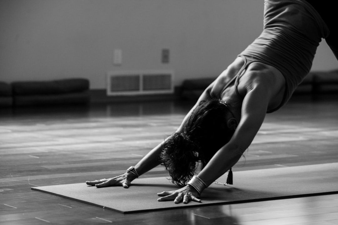 Person i framåtfälld yogaposition på en matta i en studio