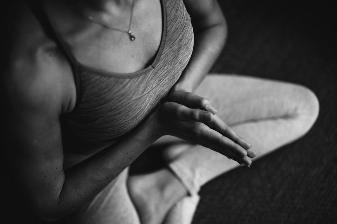 Svartvit närbild av person i sittande yogaposition med händerna sammanförda